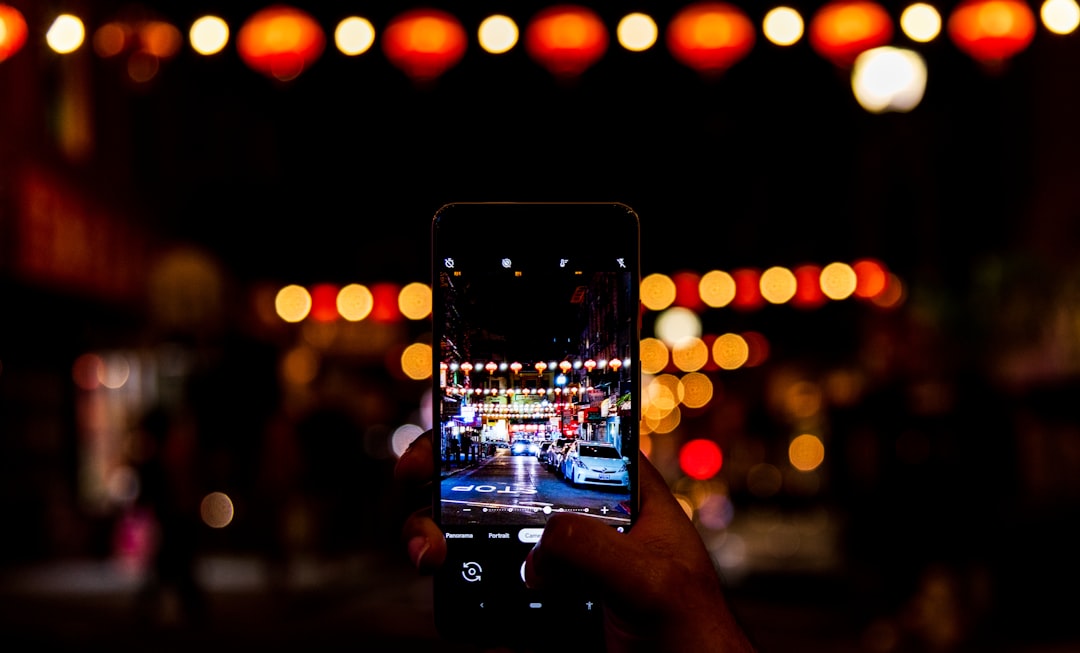 person holding black smartphone taking photo of city lights during night time instagram reels, social media dashboard, mobile phone automation